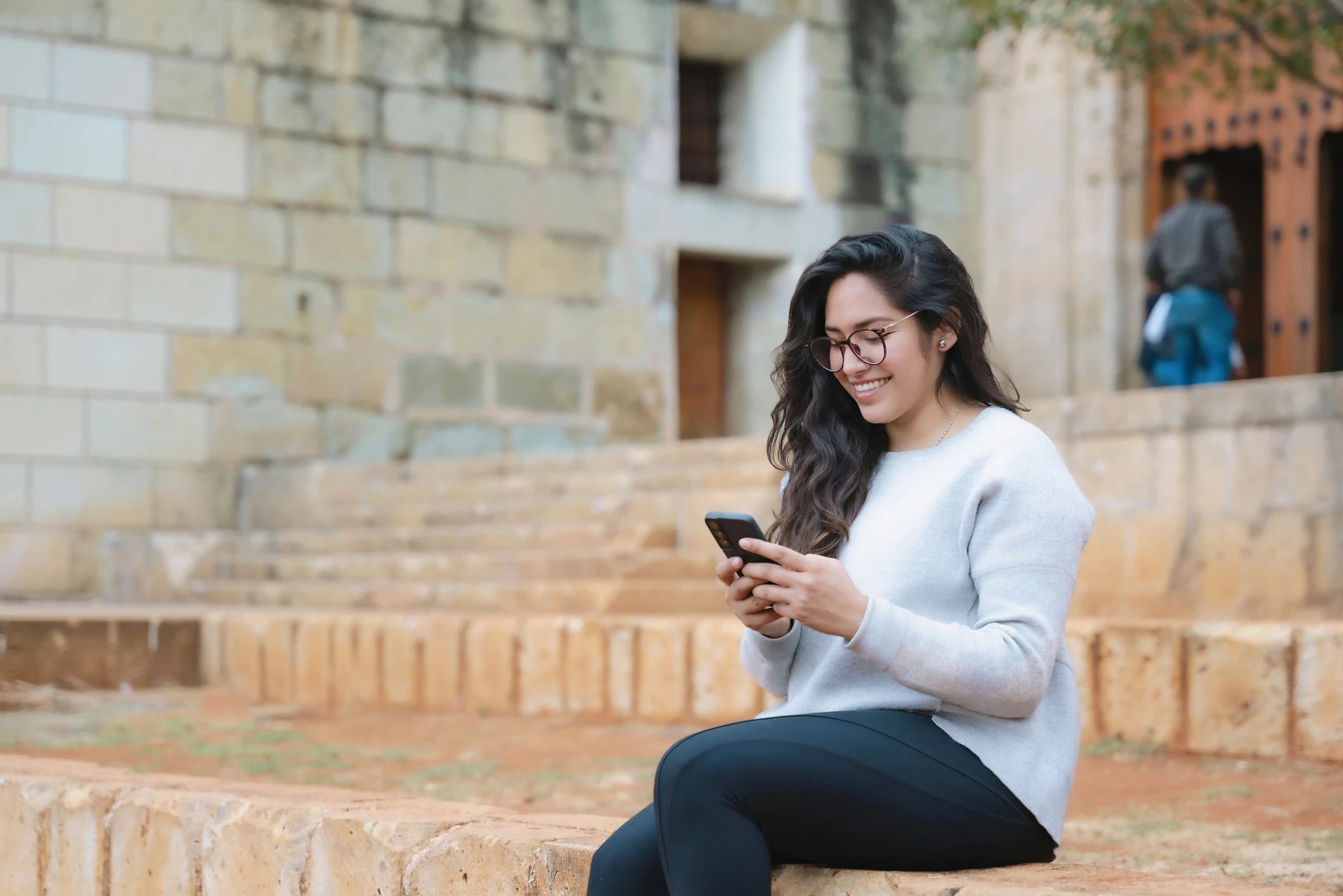 woman sitting on steps using cell phone