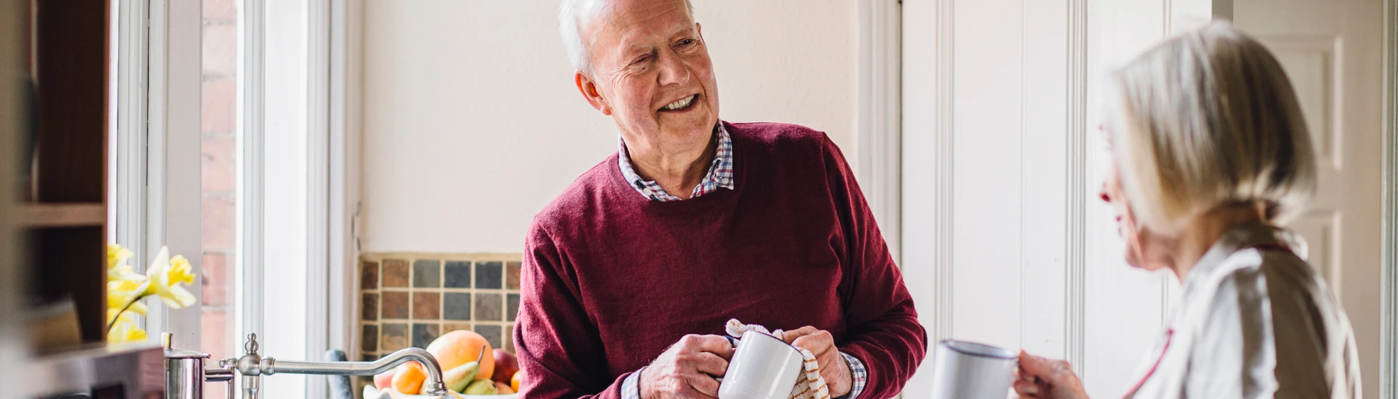 caucasian man and wife cleaning mug in kitchen
